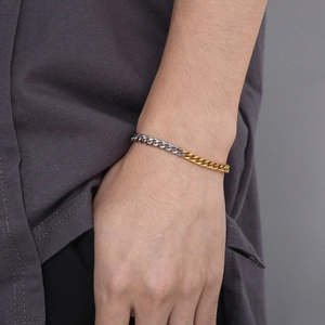 Detail of two-tone gold and silver Cuban link bracelet on a model's wrist