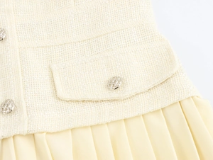 Detailopname van beige tweed stof met metalen knopen en geplooide rok