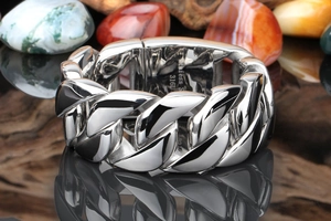 Macro shot of silver 316L stainless steel Cuban link ring on dark textured stones