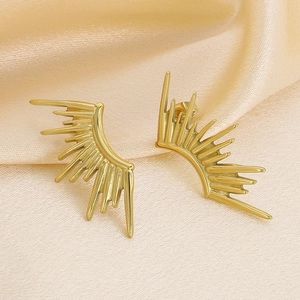 Detailed macro view of 18k gold plated sunburst earrings on elegant beige silk fabric