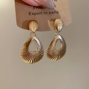Detail of gold hollow teardrop earrings with radial texture on craft card