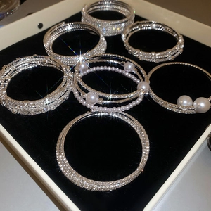 Dettaglio di bracciali elastici multistrato con strass di cristallo e perle finte in scatola