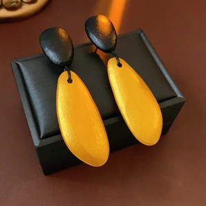 Detailed close-up of irregular wood bead drop earrings on a black leather jewelry box