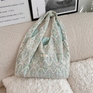Detailed close-up of light green lace embroidery canvas tote bag on soft plush surface