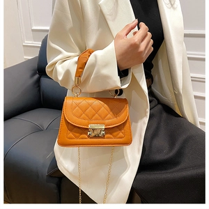 Detalle de bolso bandolera naranja acolchado con cadena dorada y cierre metálico