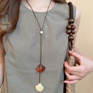 Detail of bohemian long necklace with amber and ivory shell pendants on a linen dress