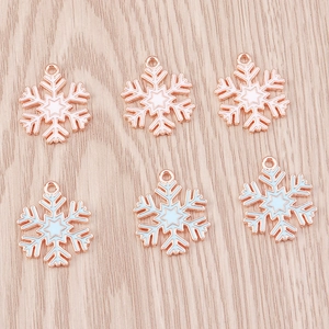Flat lay of white and light blue snowflake pendants with metal trim on wood background