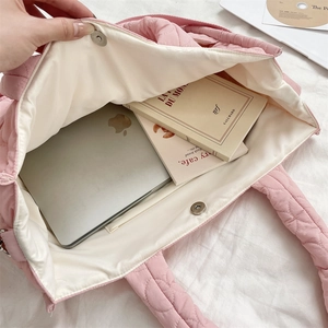 Detailed interior of pink quilted tote bag showing large capacity for laptop and books
