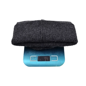 Deep grey knitted beanie on a scale showing a 94g lightweight and warm thick ribbed design
