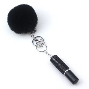 Detail of black pompom keychain with silver chain and rhinestone perfume bottle charm
