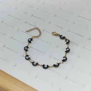 Detaillierte Makroansicht der goldenen Mond-Anhänger und Evil-Eye-Details am Armband