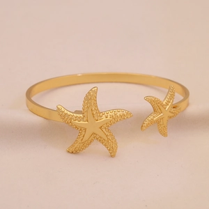 Detail eines goldenen Armreifs mit Seesternen und maritimen Muschel-Elementen