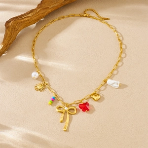 Gold butterfly bow necklace with colorful acrylic beads and sun charms on beige paper