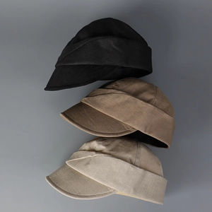 Linen newsboy caps in black, tan and beige stacked vertically on a gray background