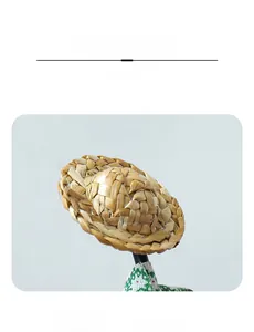 Détail d'un mini chapeau de paille tressé avec bordure florale verte sur un support noir