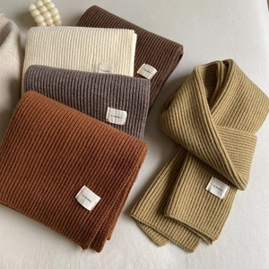 Close-up of assorted ribbed knit scarves in cream, brown, and khaki with h.modmi labels