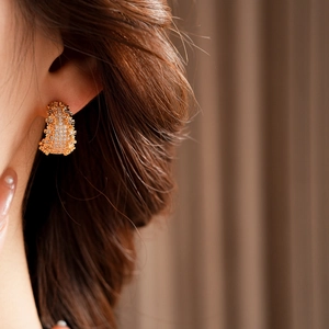 Gros plan d'une boucle d'oreille en forme de C plaquée or sertie de zircons