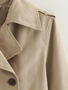 Detail of classic lapel and resin button on khaki twill trench coat for women
