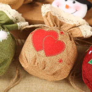 Close-up of burlap Christmas gift bag with red hearts, lace trim and snowman detail