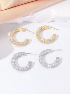 Detailed close-up of gold and silver C-shaped pavé earrings with cubic zirconia stones
