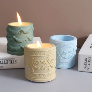 Détail de bougies cylindriques à motif flocon de neige en vert, jaune et bleu poli