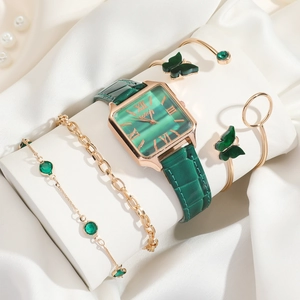 Close-up of green emerald watch set with butterfly bracelet on white silk display