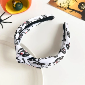 Detailed shot of a white knotted headband with skull and heart patterns on a tray