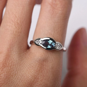 Detail of a silver ring featuring a marquise-cut blue gemstone and side diamonds