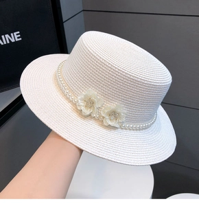 Detailed texture of white boater straw hat with elegant pearls and dual floral accents