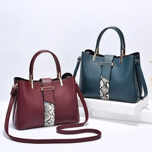Detail of burgundy and dark green textured leather handbags with stitching and metal buckles