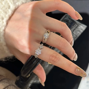 Detailed view of silver sparkling clover and snowflake rings worn on hand by a luxury bag
