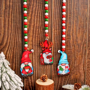 Three festive Christmas gnome wooden beaded ornaments hanging against a rustic wood background
