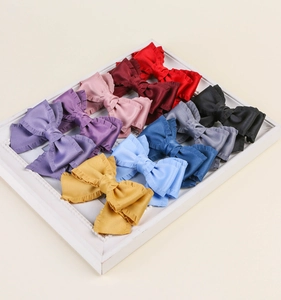 Barrettes à cheveux à nœuds en satin multicolores disposées dans un cadre blanc décoratif