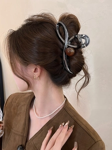 Detail view of large black metal hair claw clip with marble bead on an elegant updo
