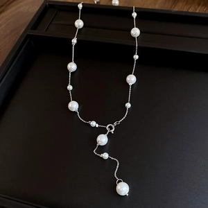 Detailed Y-shaped faux pearl necklace with silver chain on black display tray