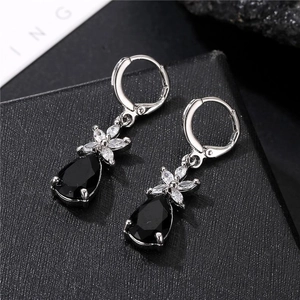 Macro shot of silver-tone teardrop earrings with black gems and clear zircon flowers