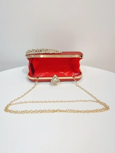 Detailed view of red glitter clutch bag with gold frame and detachable chain strap