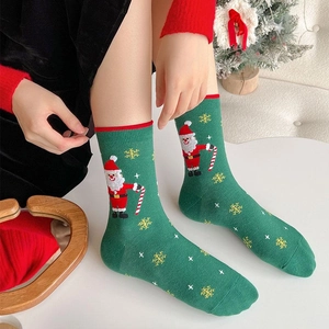 Green Christmas crew socks with Santa Claus pattern worn in a cozy holiday setting
