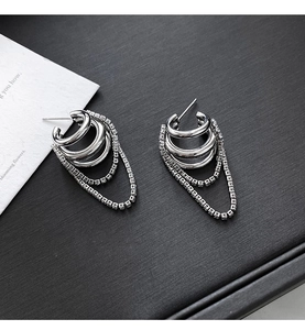 Close-up of silver multilayer chain tassel earrings with sparkling zircon on black background