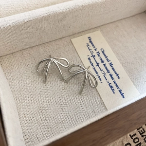 Gros plan de boucles d'oreilles nœud argentées dans un écrin à bijoux en coton et lin texturé