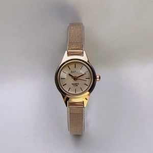Detailed close-up of a gold mesh strap and small round dial on a women's quartz watch