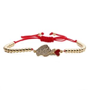 Red woven rope bracelet with gold beads, zircon hand gesture and heart charm on white background