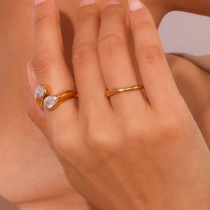 Close-up of dual pear-shaped zircon open ring and textured gold band on model hand