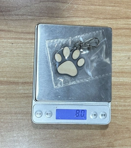 Wooden dog paw keychain weighing 8.0 grams on a digital scale for size reference