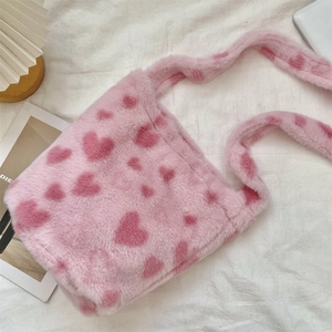 Detail of pink plush crossbody bag with heart patterns and soft fuzzy texture