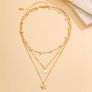 Detailed view of triple-layered gold necklace with faux pearls and textured round pendants