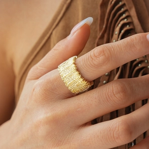 Macro detail of wide gold ring with woven texture on model finger bohemian style