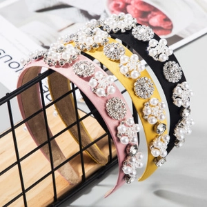 Dettaglio di cerchietti floreali rosa, gialli e neri con perle e strass luccicanti