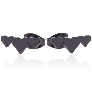 Close-up of matte black stainless steel triple heart stud earrings on white mirror