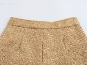 Close-up of gold tweed shorts featuring sparkling sequins and fine metallic gold thread weave